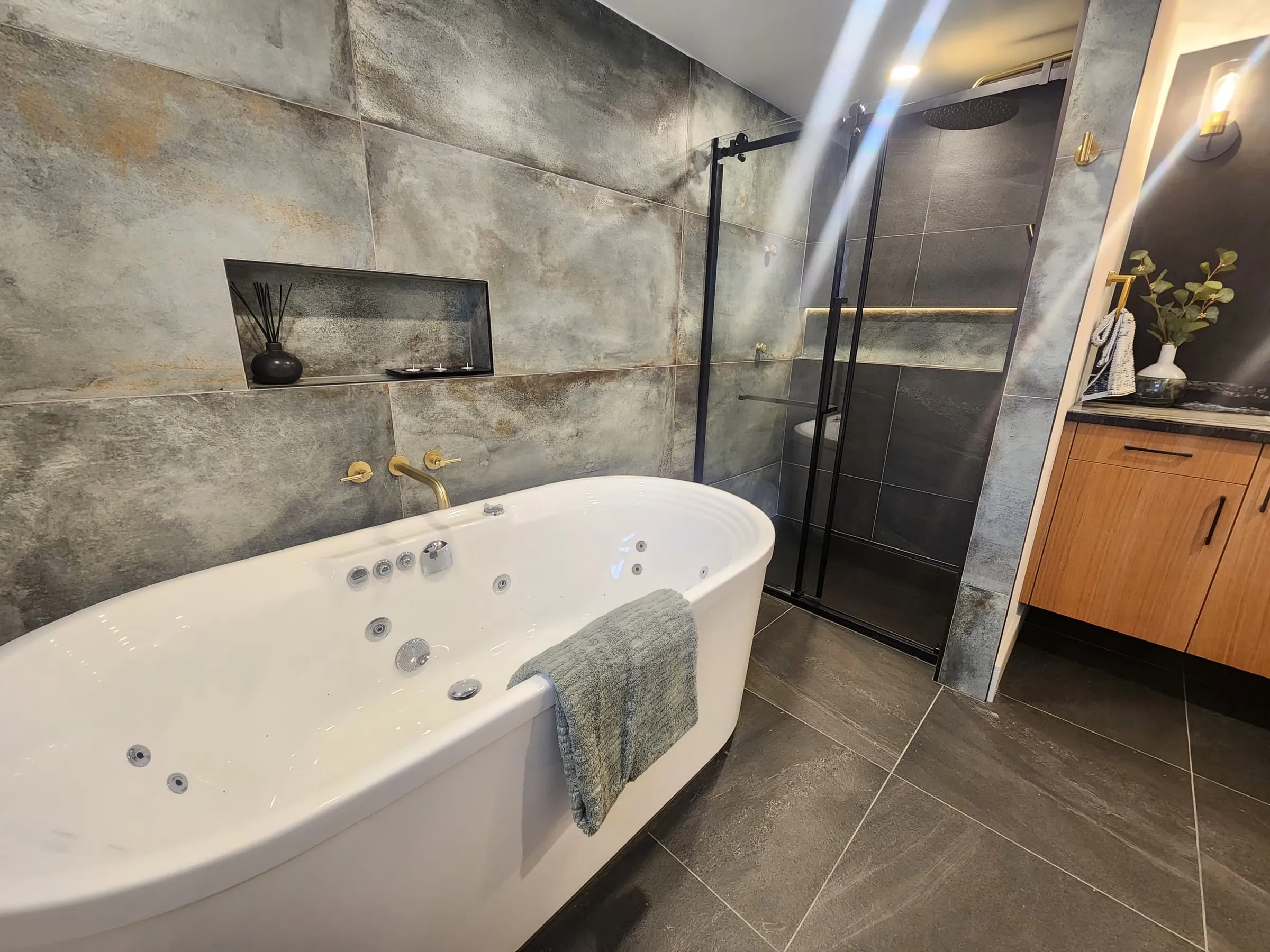 The tub in the foreground and the walk-in shower with black-framed glass behind it.