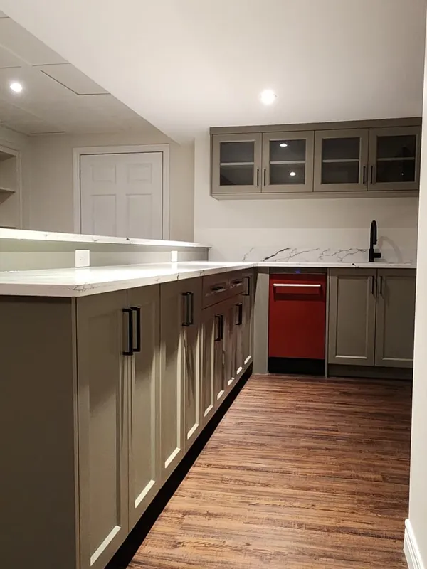 The new bar counter with sage-grey cabinets, built-in shelves along the wall and glass-front cabinets at the end.