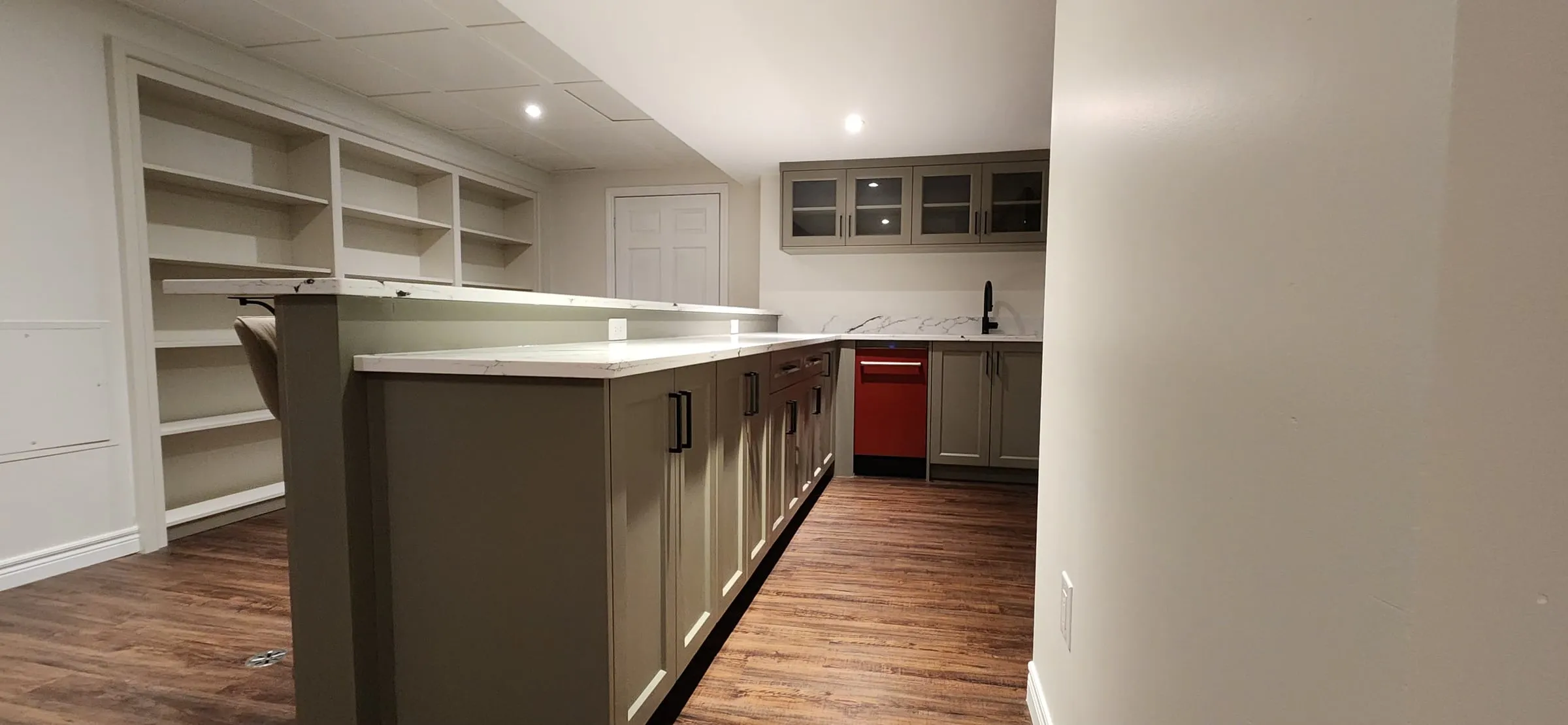 The new bar counter with sage-grey cabinets, built-in shelves along the wall and glass-front cabinets at the end.
