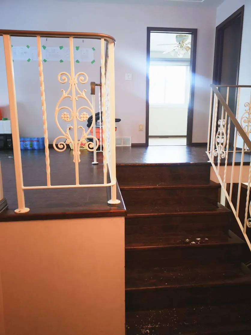 The old split-level stairs before the renovation, with dark brown treads and white scrolled metal railings.