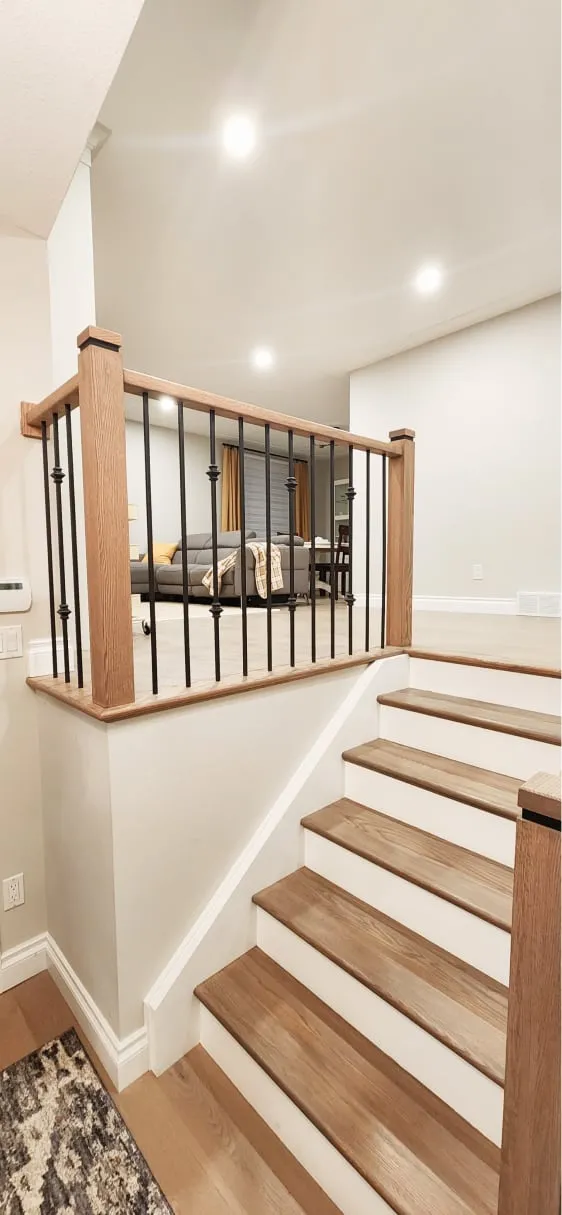 The finished stairs leading to the living room, with light wood treads, white risers and a black-spindle railing.