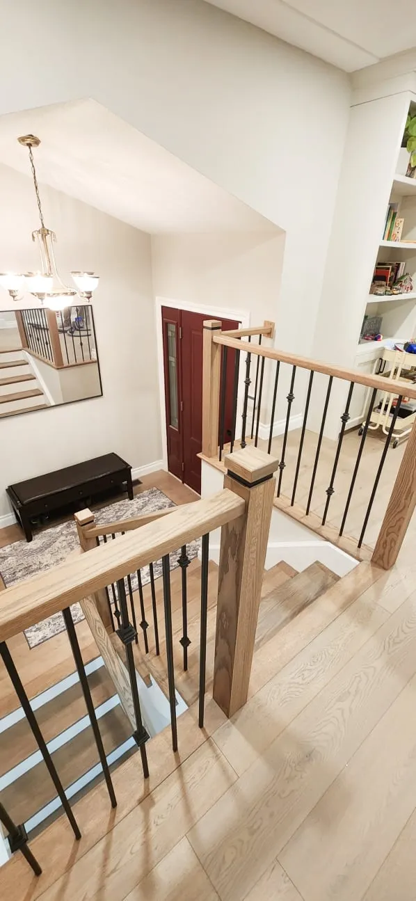The new staircase seen from the upper floor, looking down to a front entry with a red door.