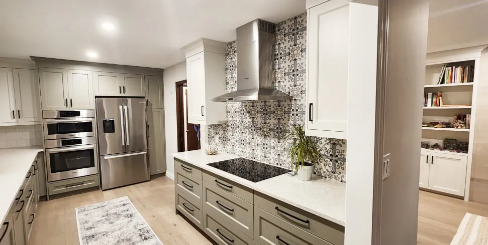 The finished kitchen opening onto the living area, with a black cooktop, patterned backsplash and built-in bookshelves beyond.