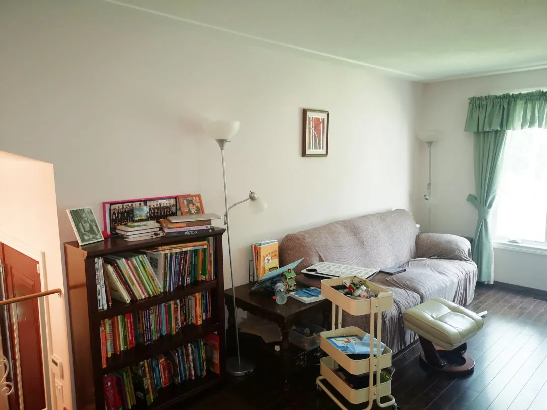 The old living room before the work, with a dark bookcase, a covered couch and two floor lamps.