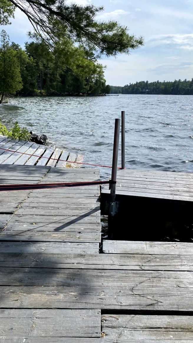 The old dock before the rebuild, with weathered grey boards, uneven gaps and a lake beyond.