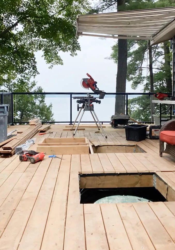 A new wood deck under construction, with an opening that shows the septic tank's green lid below.
