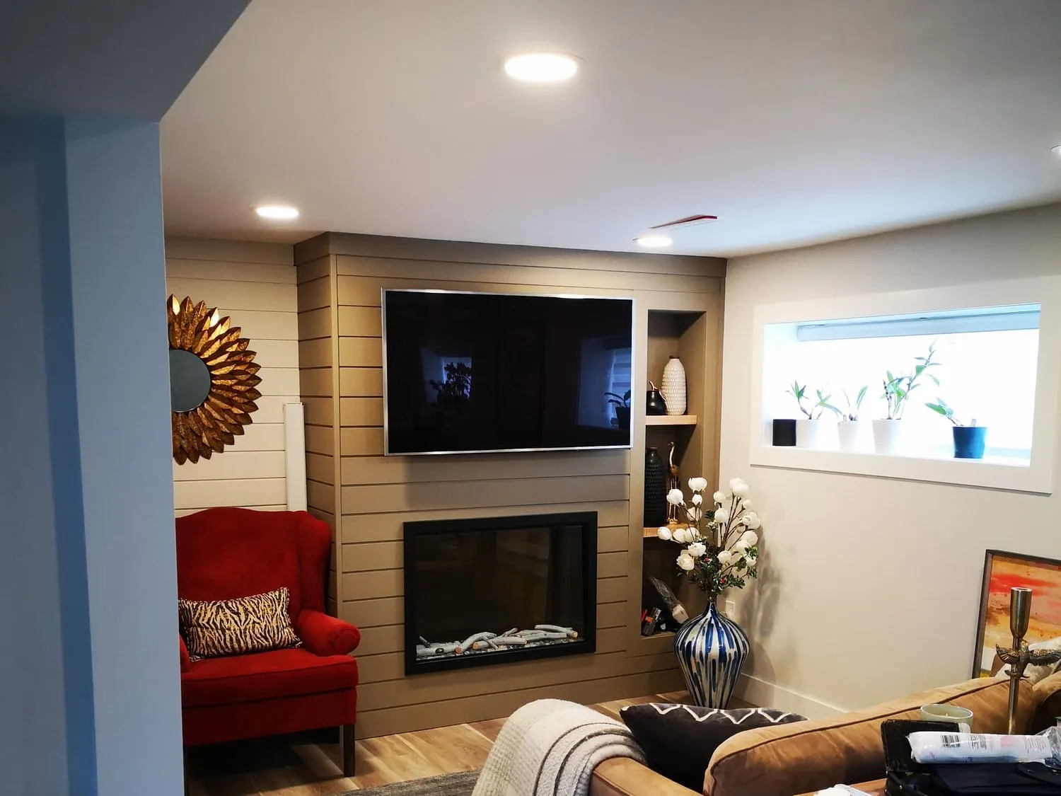 A cosy family room with a taupe shiplap fireplace wall and a mounted TV