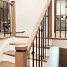 The finished staircase with light wood treads, white risers and black metal spindles