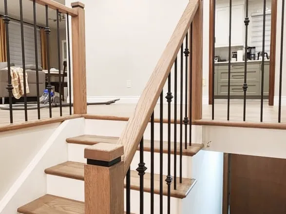 The finished staircase with light wood treads, white risers and black metal spindles
