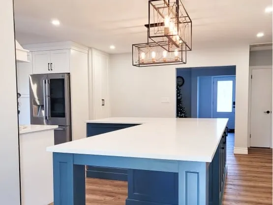 The finished open space with a large L-shaped blue island where a load-bearing wall used to stand