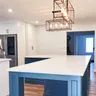 The finished open space with a large L-shaped blue island where a load-bearing wall used to stand